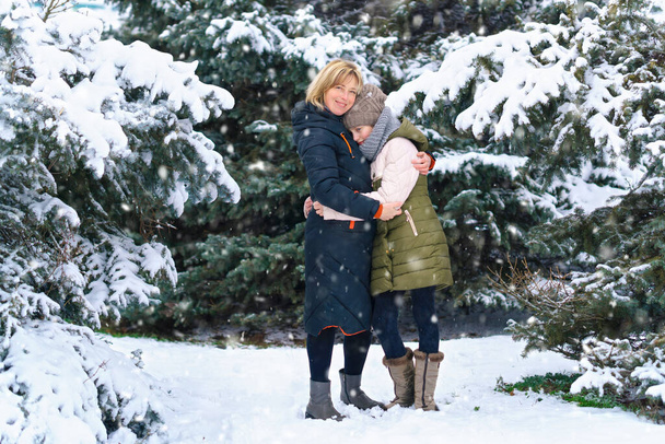 retrato familiar de madre e hija en un bosque de invierno, un padre y un hijo, hermosa naturaleza con abetos nevados brillantes - Foto, Imagen