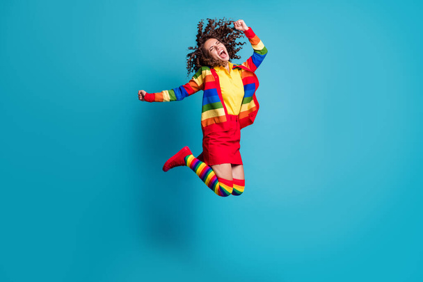 Full body photo of crazy young girl wear skirt jump have fun fists hand scream shout happy smile isolated over blue color background - Foto, Bild