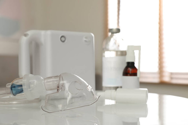 Face mask near nebulizer and medications on white table indoors. Inhalation equipment - Foto, Imagem