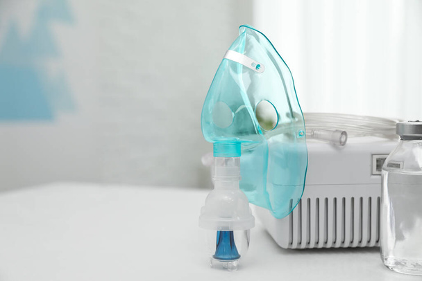 Modern nebulizer with face mask and medicine on white table indoors, space for text. Inhalation equipment - Фото, зображення