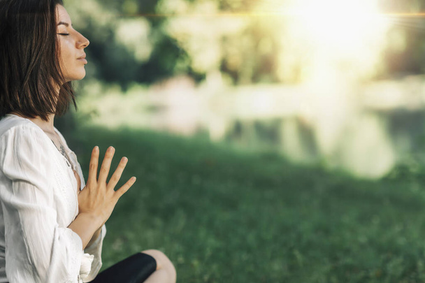 "静けさ"だ。穏やかな若い女性蓮のポーズは、水によって瞑想に座っている。祈りの場で手を合わせる - 写真・画像