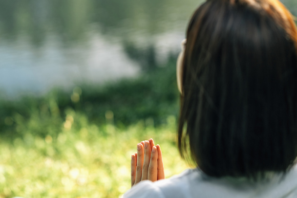 Mindful Young woman, feeling grateful, meditating, sitting by the water, hands in prayer position - Foto, Imagem