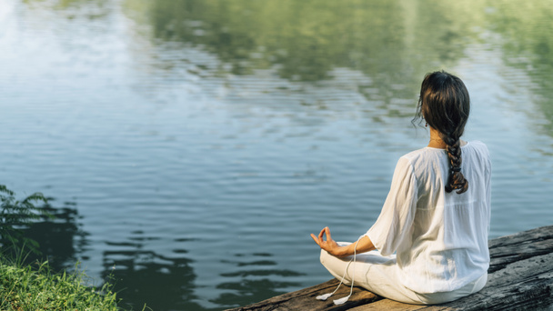 Yoga υποχώρηση. Γαλήνια νεαρή γυναίκα κάθεται στη θέση του λωτού και διαλογίζεται στη λίμνη - Φωτογραφία, εικόνα