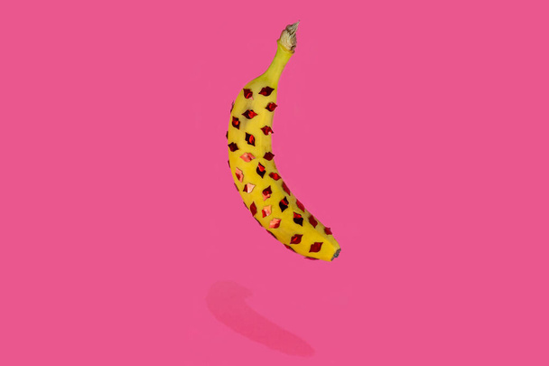 Floating banana with little kiss lips on it. Pink background. Creative love concept - Фото, зображення