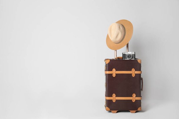 Vintage travel suitcase with hat and camera on light grey background, space for text. Summer vacation - Foto, Imagem