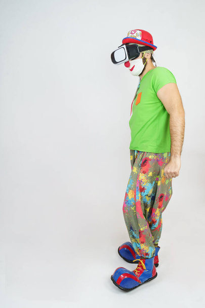 Holiday and fun concept. The clown is playing, he has virtual glasses on his head. Isolated on white - Foto, immagini