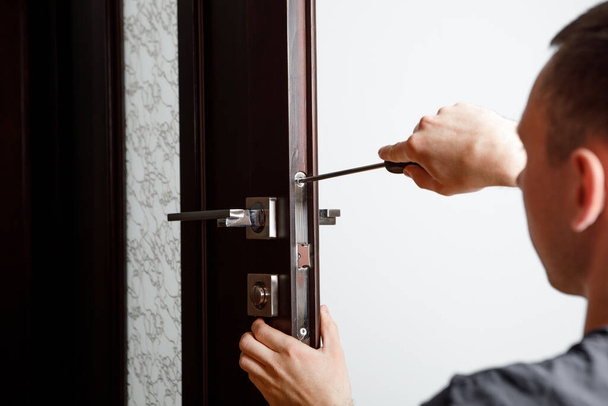 man repairing the doorknob. Carpenter working on lock installation with out the door knobs wood door - Фото, зображення