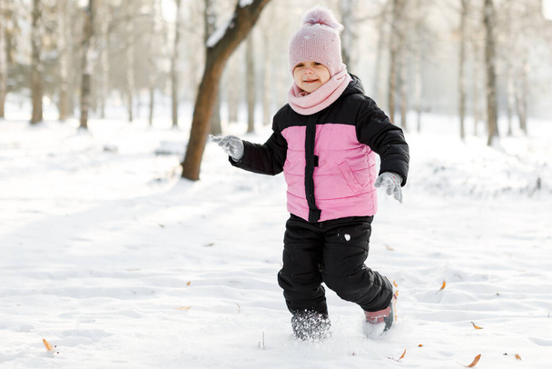 little girl playing with snow on the street - Foto, Imagen