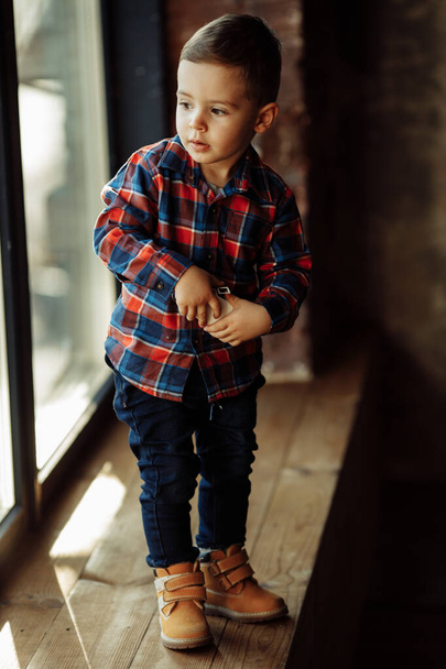portrait of a little boy in a shirt on window sill  - Photo, Image