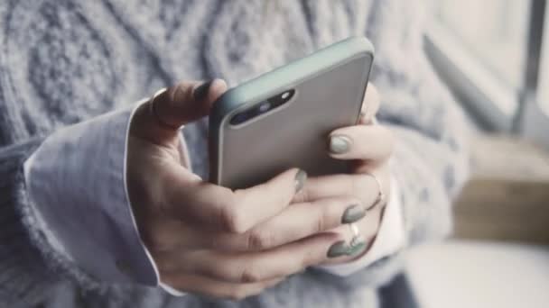 Fechar imagens de mulher digitando mensagem no smartphone perto da janela - Filmagem, Vídeo