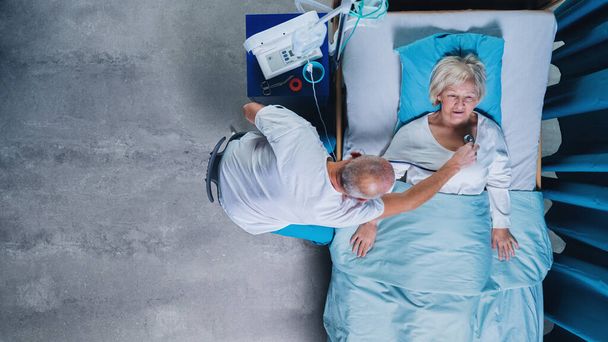 Top view of doctor with stethoscope examining patient in bed in hospital. Copy space. - Valokuva, kuva