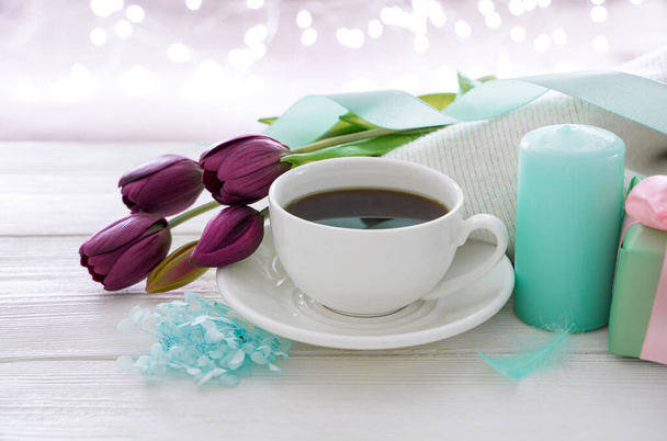 8 de marzo, tulipanes, café y una taza de café en el fondo de una guirnalda ardiente. - Foto, imagen