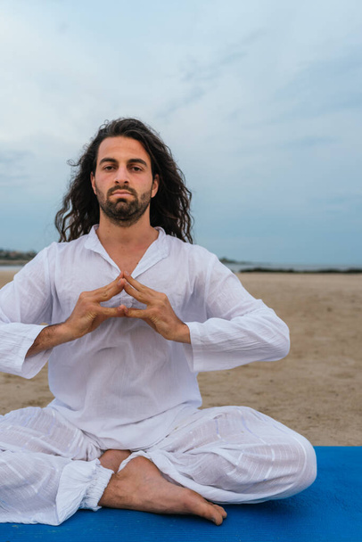 Foto de stock de hombre adulto con el pelo largo haciendo yoga posa en la playa. - Foto, Imagen