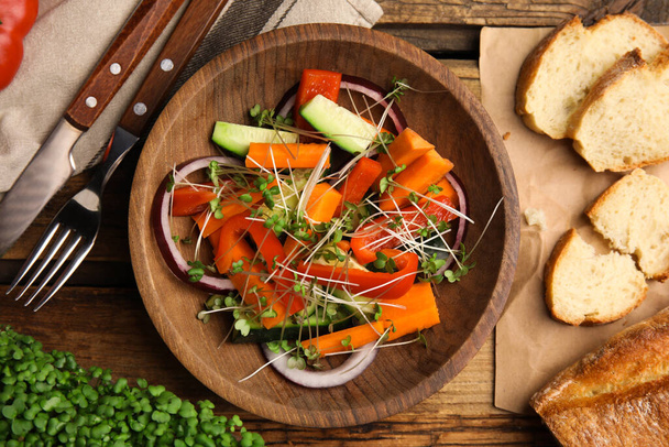 Salad with fresh organic microgreen in bowl on wooden table, flat lay - Fotoğraf, Görsel