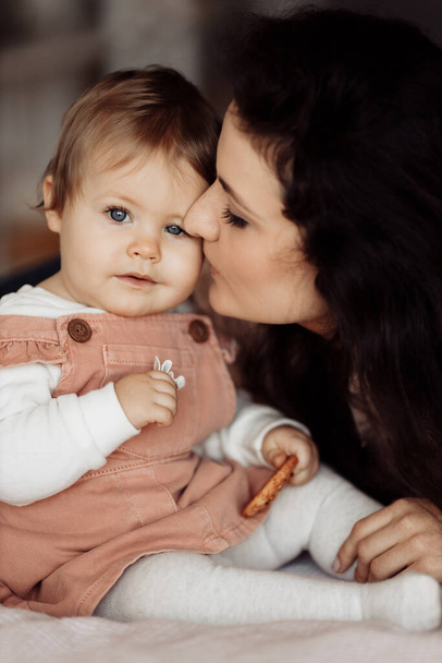 young mother kissing her little daughter eating cookie - Fotografie, Obrázek