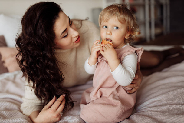 young mother with her little daughter eating cookie - Foto, Imagen