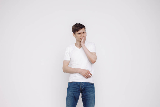 Портрет мужчины с зубной болью в белой футболке на белом фоне. - Фото, изображение