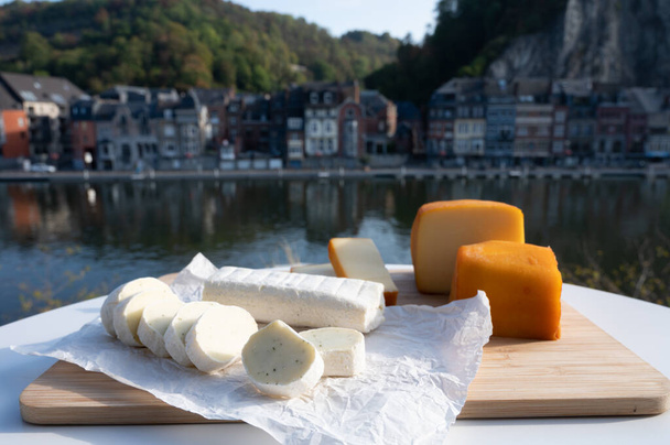 Collection de fromages, savoureux fromages d'abbaye belges à base de bière trappiste brune et fines herbes et vue sur la rivière Maas à Dinant, Wallonie, Belgique - Photo, image