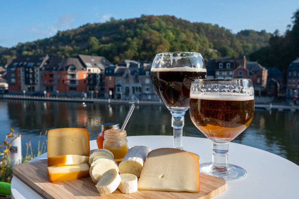 Склянка міцного бельгійського абатства і смаки сирів, виготовлених з траппістського пива і чудових трав'яних трав з видом на річку Маас в Дінанті, Валлонія, Бельгія. - Фото, зображення