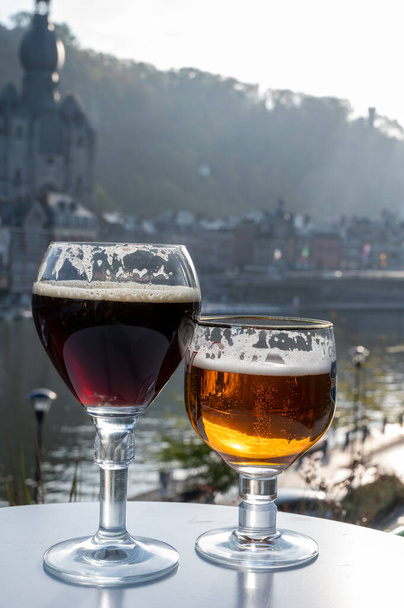 Πίνει σκούρα και δυνατή βελγική μπύρα αβαείου με τυριά σε ηλιόλουστη μέρα με ωραία θέα στον ποταμό Μάας και την πόλη Dinant, Βέλγιο - Φωτογραφία, εικόνα