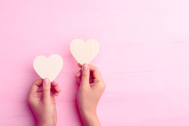 Hand holding heart shape for giving on pink background, Valentine day - Foto, imagen