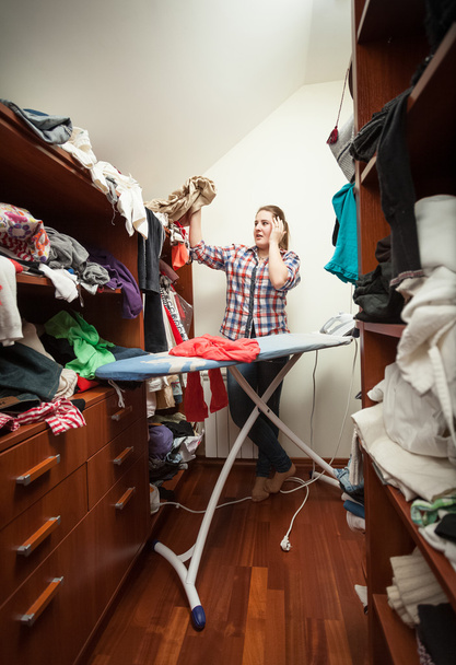gospodyni patrząc na nie wyprasowane ubrania w szafie - Zdjęcie, obraz