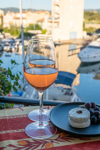Ochutnávka místního růžového vína a měkkého francouzského kozího sýra v létě s plachetnicemi útočiště Port Grimaud na pozadí, Provence, Var, Francie - Fotografie, Obrázek