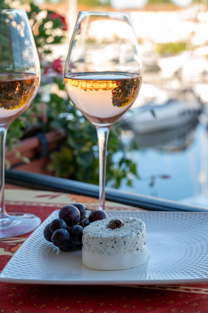 Ochutnávka místního růžového vína a měkkého francouzského kozího sýra v létě s plachetnicemi útočiště Port Grimaud na pozadí, Provence, Var, Francie - Fotografie, Obrázek