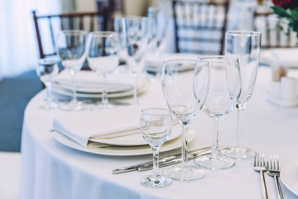 レストランでナプキングラスとディナーのためのファンシーテーブルセット、豪華なインテリアの背景。白いテーブルクロステーブルにケータリングサービスで配置された食品のための結婚式エレガントな宴会の装飾やアイテム - 写真・画像