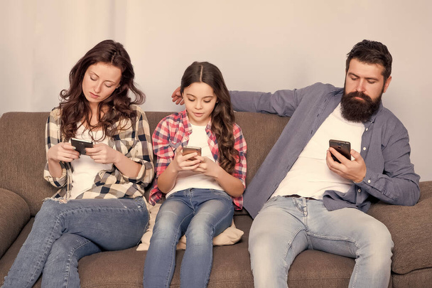 Online family. Family spend weekend online. Child little girl use smartphone with parents. Family surfing internet. Mom dad and daughter relaxing on couch. Family leisure. Play game application - Foto, Bild