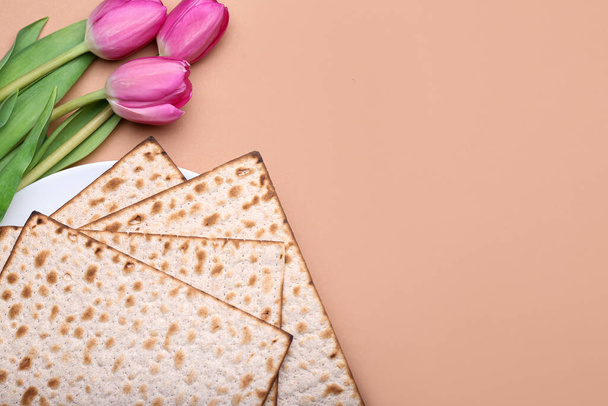 Plate with Jewish flatbread matza for Passover and flowers on color background - Foto, Imagem