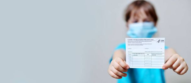 banner girl tiene una tarjeta de registro de vacunación y viales de vacuna contra el virus corona. Pasaporte de inmunidad al coronavirus en manos de un niño. Pasaporte sanitario como prueba de recuperación de COVID-19 - Foto, imagen
