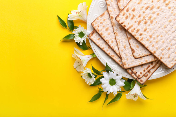 Prato com pão fosco judeu matza para a Páscoa e flores no fundo de cor - Foto, Imagem