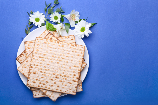 Teller mit jüdischem Fladenbrot zum Pessach und Blumen auf farbigem Hintergrund - Foto, Bild
