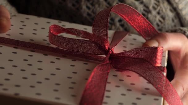 A kezek egy karácsonyi ajándékot tartanak masniba csomagolva. - Felvétel, videó