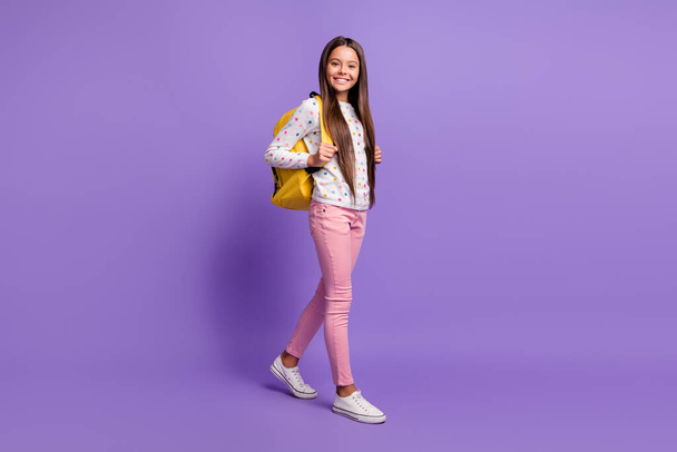 Full length body size photo of preteen girl with long hair carrying yellow backpack smiling happily isolated on bright violet background - Zdjęcie, obraz