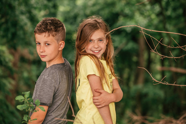 Portret van klein schattig meisje en jongen in het bos. Ze besteden goede tijd in het voorjaar natuur.Selectieve focus. - Foto, afbeelding