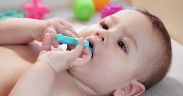 bebé, concepto de la infancia - primer plano de sonreír feliz Bebé juega con un mordedor. Cortar los dientes. Primeros dientes. Joy mordida de bebé sin dientes de 7 meses, roe el juguete del mordedor - Imágenes, Vídeo