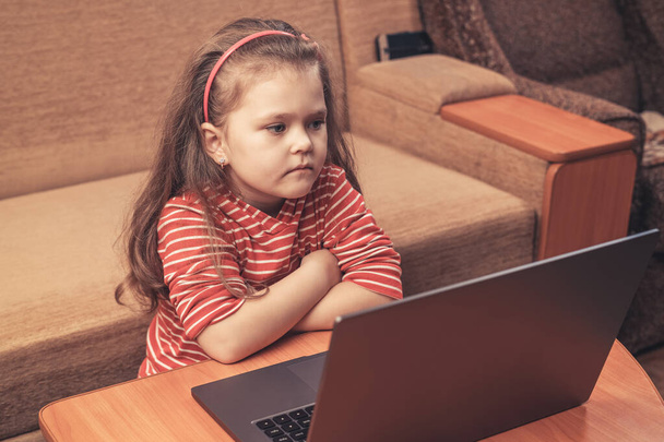 Little girl uses laptop for distance learning or for entertainment. - Foto, afbeelding