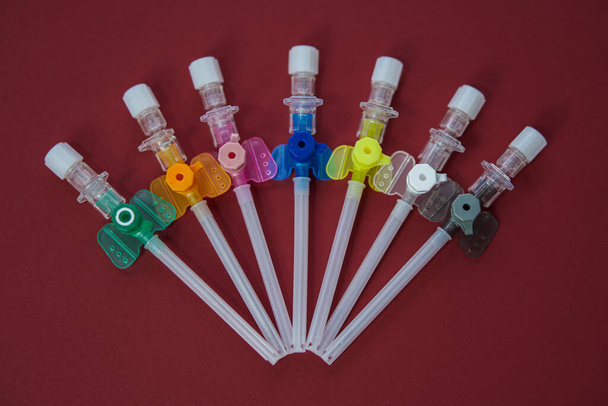 intravenous catheters on a red background, shot close-up. multicolored catheters have different diameters - from the smallest to the largest - Foto, Imagen