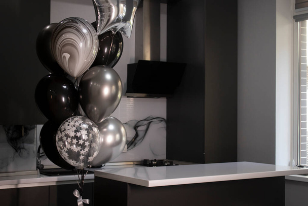Hoek van stijlvolle Minimalistische grijze keuken, donkergrijze kasten, witte aanrechtbladen en bar. zwart-witte ballonnen. Hoge kwaliteit foto - Foto, afbeelding