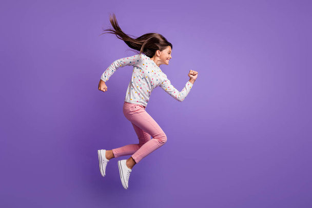 Full length body size side profile photo of jumping high hurrying up preteen girl smiling isolated on vibrant violet color background - Фото, зображення