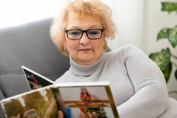Women watching family album at home, elderly woman watching photobook - Fotoğraf, Görsel