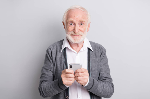 Portrait of old white hair optimistic man hold telephone wear dark sweater isolated on grey background - Foto, Imagem
