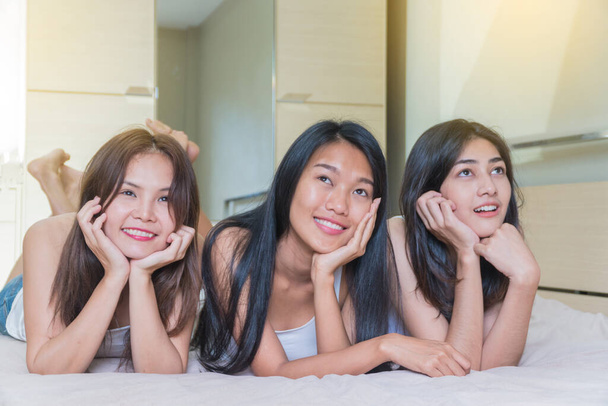 Three beautiful women lying on the bed and expression of ideas. - Photo, Image