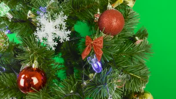 Un árbol de Navidad decorado con bulbos y juguetes está girando sobre un fondo verde - Metraje, vídeo