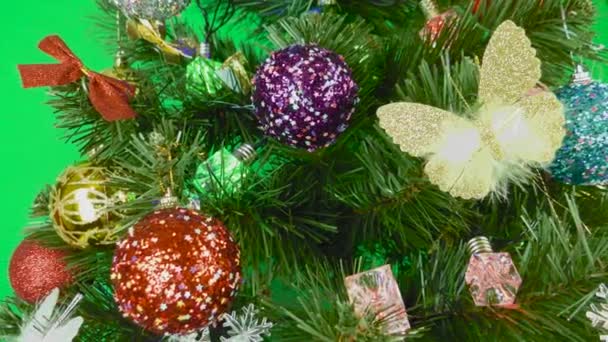 Χριστουγεννιάτικο δέντρο διακοσμημένο με λαμπτήρες και παιχνίδια περιστρέφεται σε ένα πράσινο φόντο - Πλάνα, βίντεο