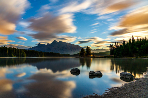 Twee Jack Lake bij zonsopgang, sterrenhemel en kleurrijke wolken weerkaatst op het wateroppervlak. Prachtig landschap in Banff National Park, Canadese Rockies, Alberta, Canada. - Foto, afbeelding