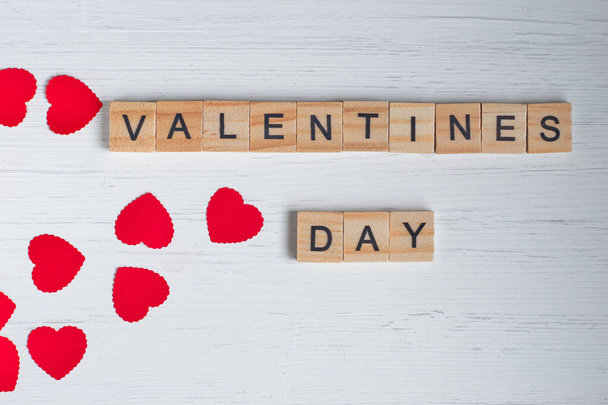 「バレンタインデー」という言葉のトップビューは、古い白い木製の背景に正方形の木製のタイルと赤の小さな心からレイアウト. - 写真・画像