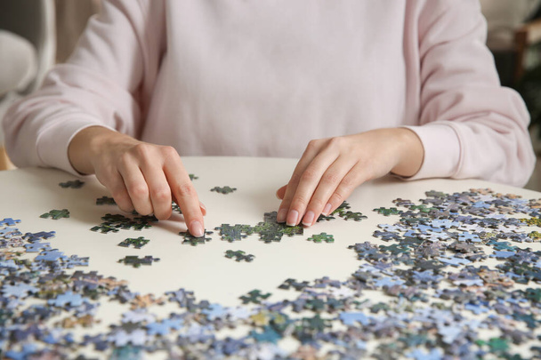 Young woman playing with puzzles at table, closeup - Fotó, kép